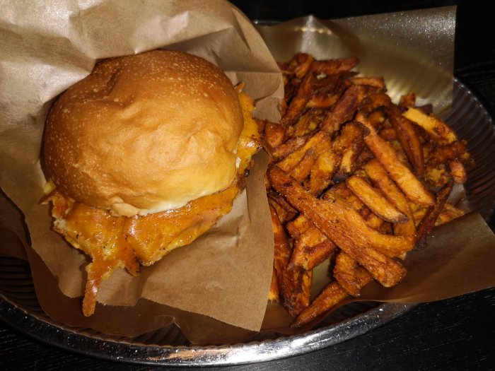 Hamburgare med smält ost i bröd och en sida av pommes frites.