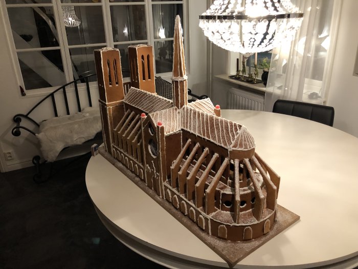 Pepparkakshus som föreställer katedralen Notre Dame på ett vitt matbord.