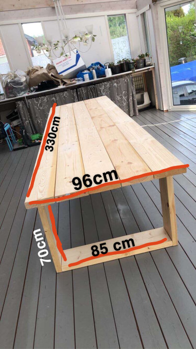 Ett nybyggt träbord med måttmarkeringar på 330 cm längd, 96 cm bredd och 70 cm höjd, placerat på en terrass.