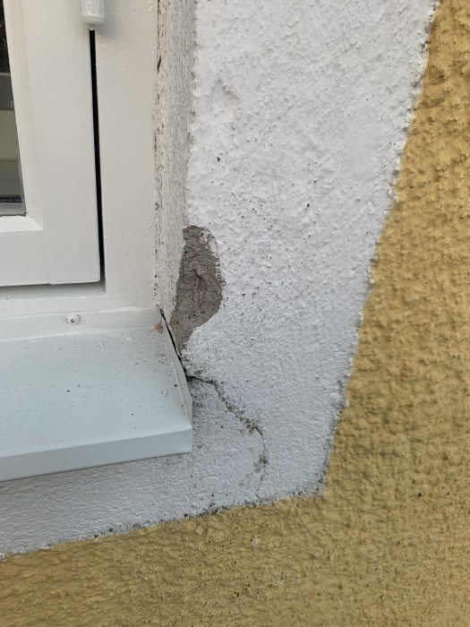 Närbild på kanten av ett renoverat fönster där en vit plåt möter ojämn putsad vägg, med synligt gap och ett märkligt veck på plåten.