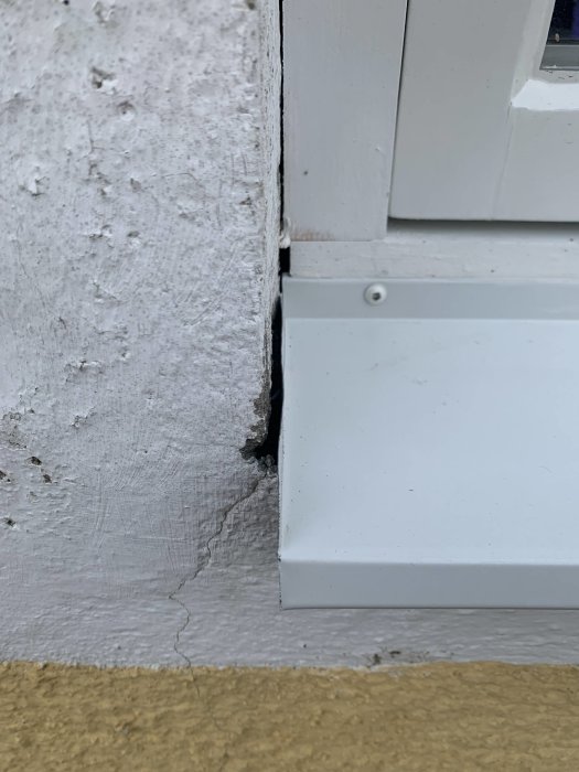 Gap mellan vit fönsterbleck och putsad vägg, med synligt ojämnt mellanrum och veck på plåten.