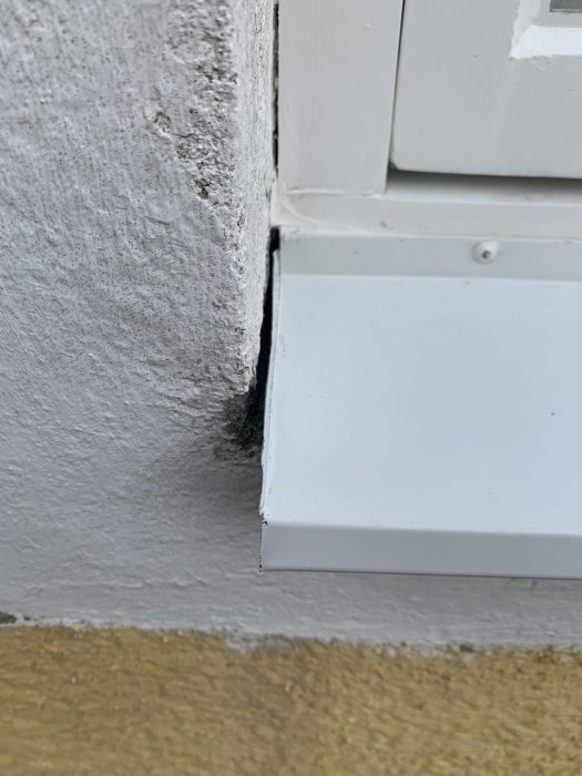 Närvarande bild visar ett närbild på ett renoverat fönsterbleck med ojämnt gap mot putsad vägg.