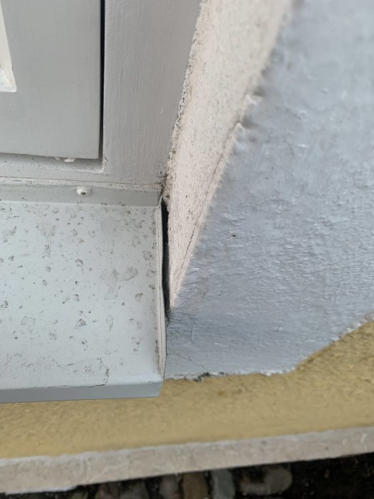 Närbild av ett renoverat fönsterbleck med ojämnt gap mellan plåt och putsad vägg.