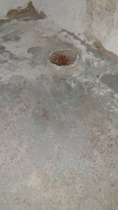 Ett öppet rör sticker upp från ett källargolv täckt med cement och klinkersrester.