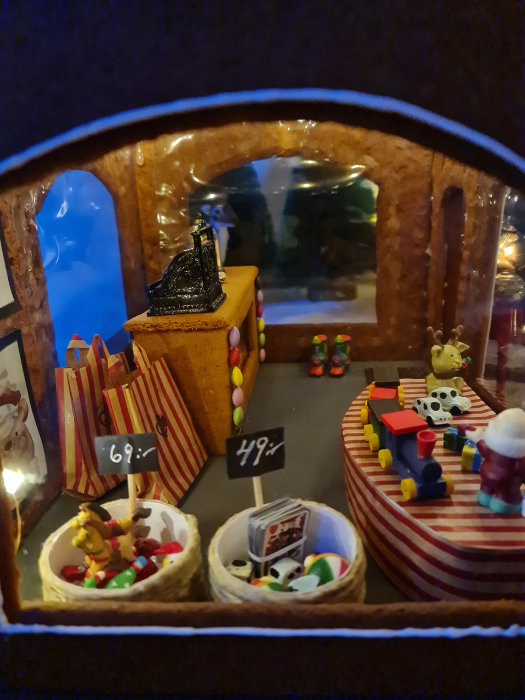 En miniatyrmarknad i en pepparkaksby med prisskyltar och små figurer.