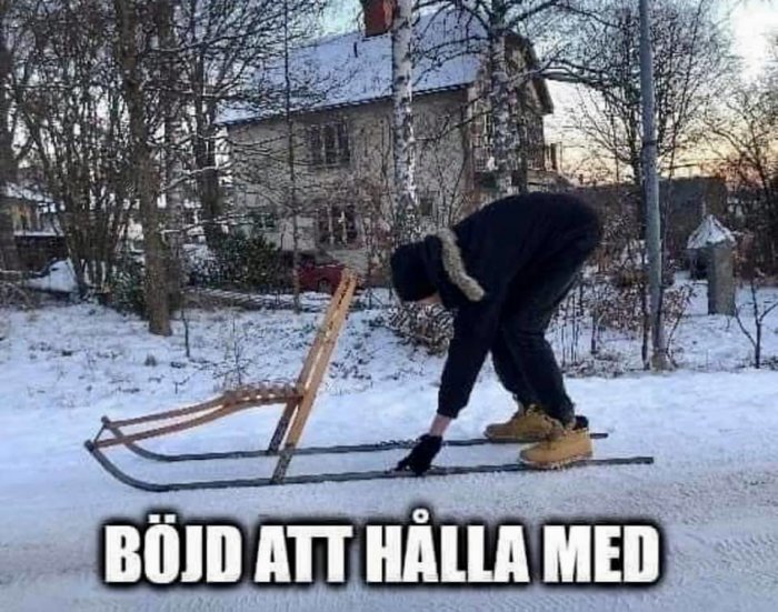 Person böjer sig ner för att fixa en traditionell sparkstötting på en snöig väg.