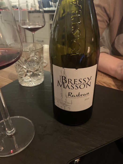 Flaska Bressy Masson Rasteau vin årgång 2020 på bord med vinglas i bakgrunden.