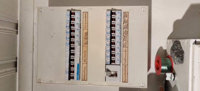 Elcentral med öppen dörr visar säkringar och etiketter för anslutna kretsar och apparater.