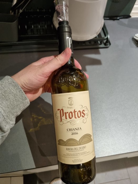 Hand håller en flaska Protos Crianza 2016 vin från Ribera del Duero.