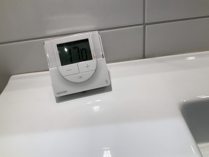 Uponor termostat visar 17 grader på vit bänkskiva i badrum.