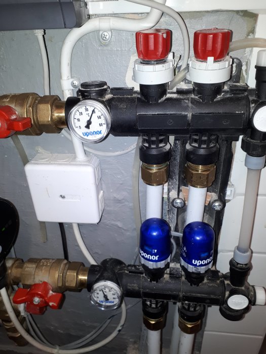 Golvvärmesystem med Uponor termostatventiler, manometrar och cirkulationspump.
