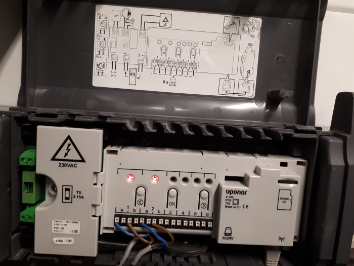 Uponor Smatrix Wave X-165 kontrollenhet för golvvärme med öppet lock och synliga anslutningar.