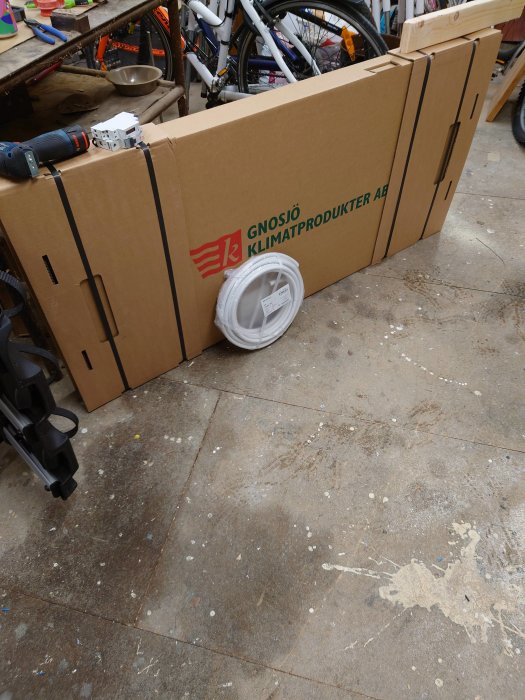 Emballage från Gnosjö Klimatprodukter AB med synligt ventilationsgaller i verkstadsmiljö.