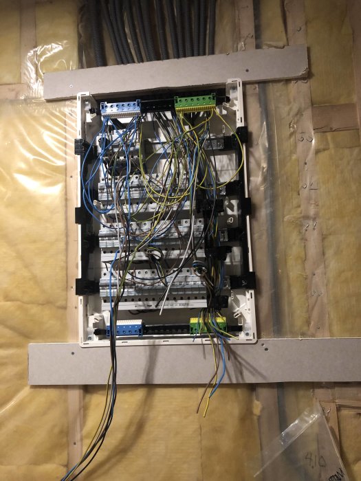 Elcentral under installation med öppna säkerhetsbrytare och oorganiserade elektriska kablar.