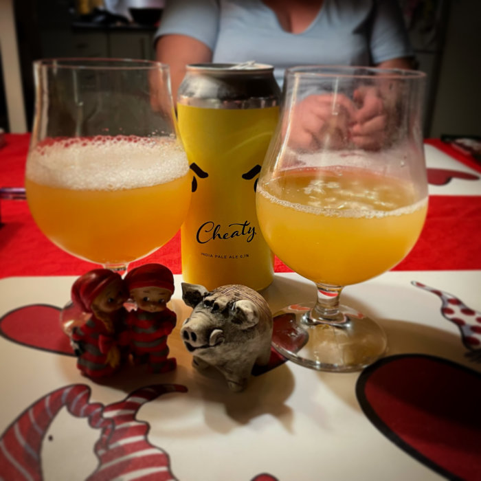 Två glas med öl, en ölburk och julfigurer på ett bord framför en person.