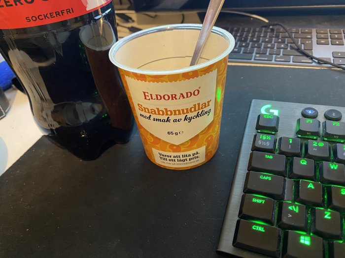Snabbnudlar från Eldorado vid en dator med tangentbord och en sockerfri dryck.