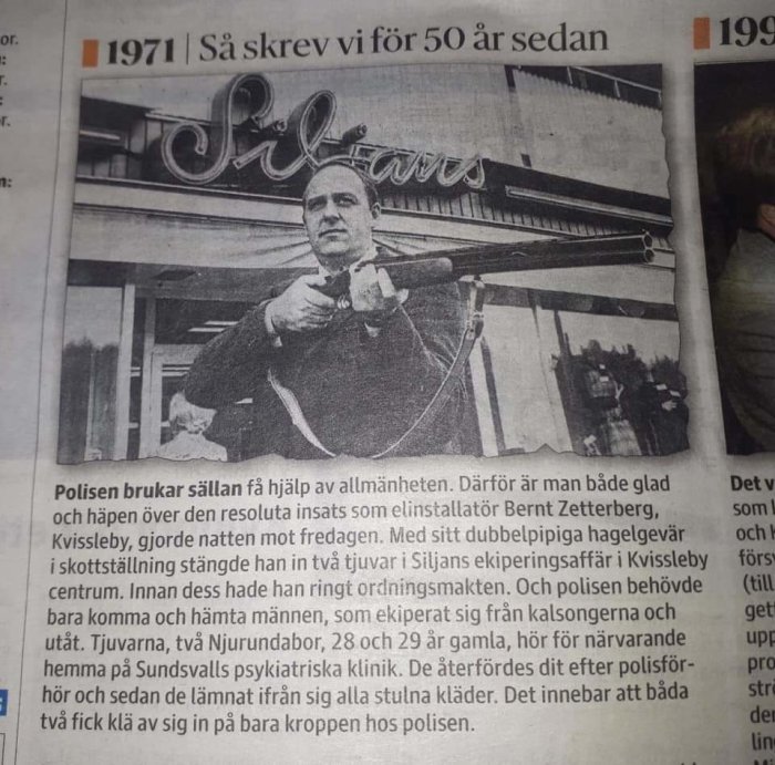 Äldre tidningsartikel med bild av en man som håller ett dubbelpipigt hagelgevär framför en butiksfasad.