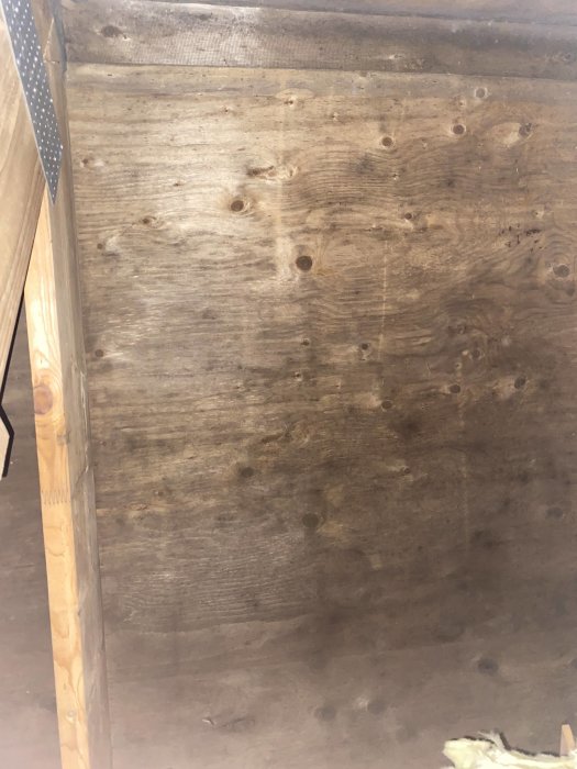 Trägolv på vind med synliga hål och märken, behov av inspektion för bedömning av skick.