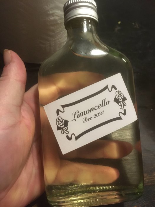 Flaska med hemgjord limoncello, märkt "Dec 2021", innehållandes skivor av frukten buddhas hand.