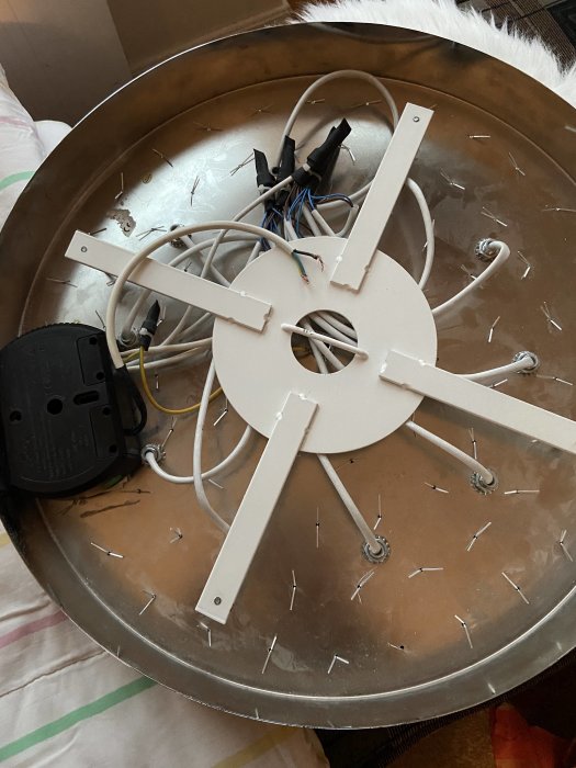 Öppen taklampa med osynliga halogenlampor, synlig kabelanslutning och en dimmerkoppling, på ett otydligt underlag.