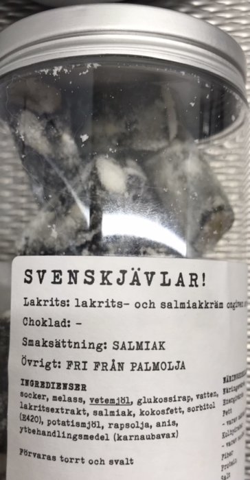 Burk med lakrits och salmiakkarameller, etikett med ingredienser och text "SVENSKJÄVLAR".