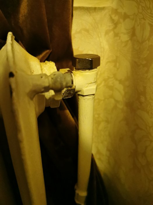 Gammalt värmelement utan reglervred, endast en avslutande mutter synlig.