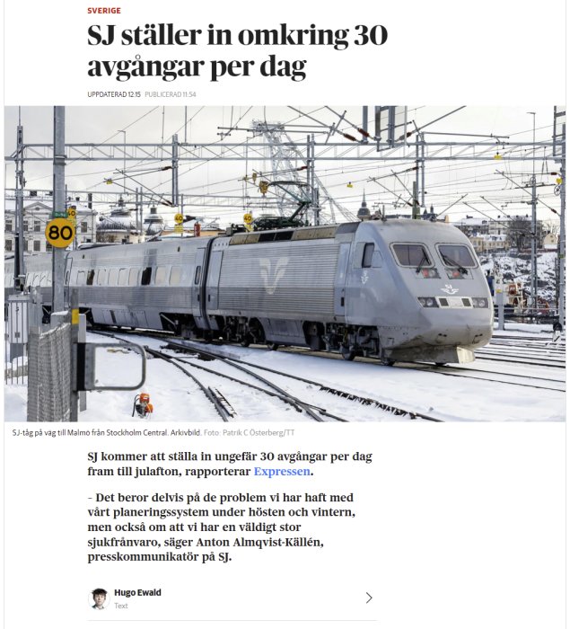 SJ-tåg vid plattform täckt av snö med hastighetsskyltar och kontaktledningar i bakgrunden.