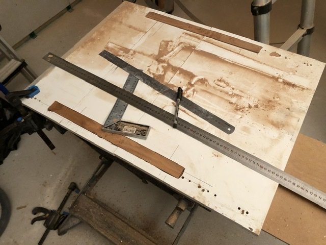 Trälist och verktyg på ett smutsigt bord i en verkstad, indikerar reparation eller hantverksarbete.