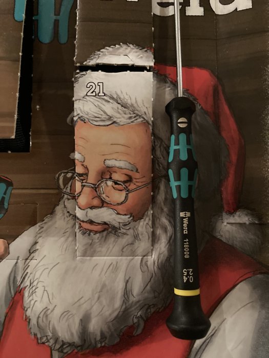 Advent calendar torn open at day 21 with an illustration of Santa Claus and a precision screwdriver resting on top.