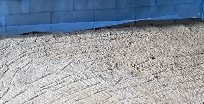 Grovt gjutet betonggolv i garage som behöver slipas för att bli jämnt.