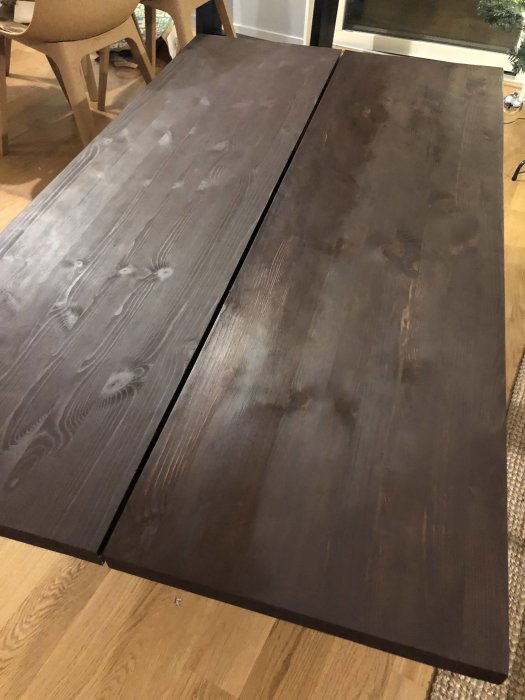 Bordskiva av furuhyllplan med ojämn betsning och områden som inte torkat ordentligt.