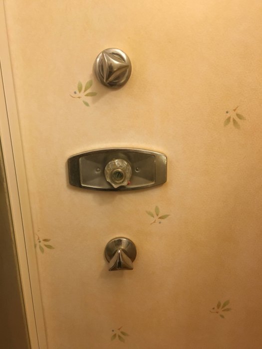 Väggmonterad duschblandare med en vred ovanför och en knopp nedanför, eventuellt av märket Grohe.