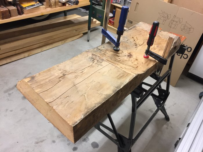 Ett gammalt golvplank från 1600-talet fastklämt på ett arbetsbord redo för hantverk.