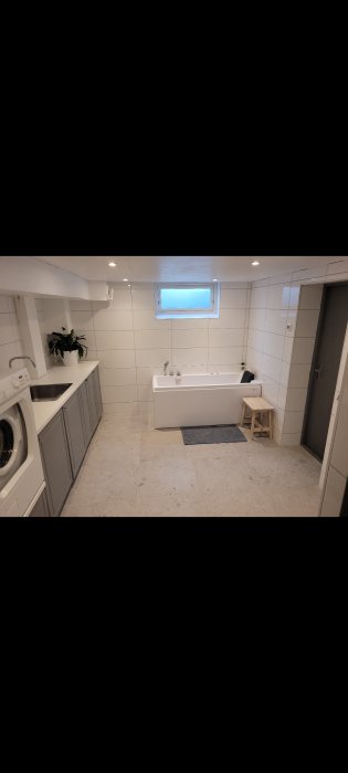 Nyrenoverat badrum med badkar, tvättmaskin, och inbyggd förvaring.