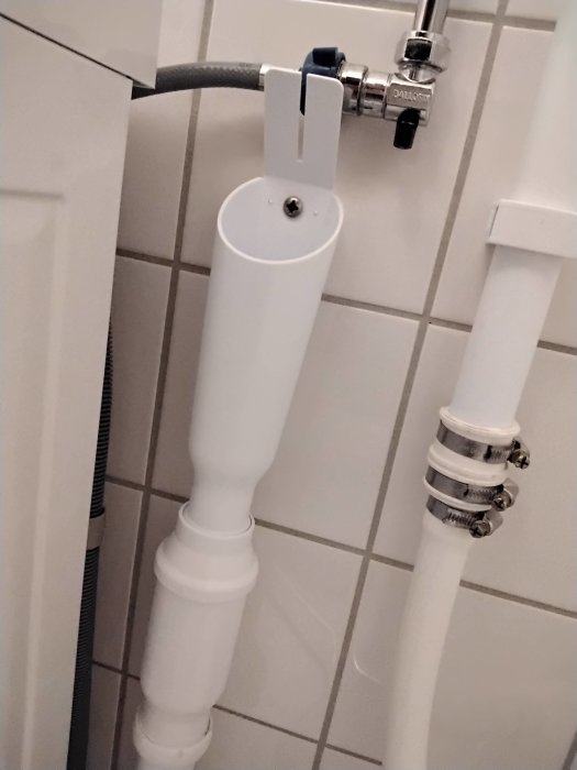 Tvättmaskinslang insatt i stigröret i badrum, möjligen osäker anslutning.