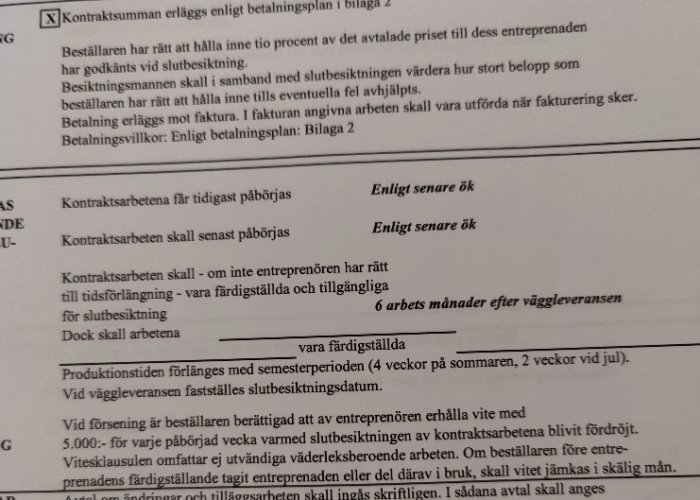 Närbild på ett byggkontrakt som beskriver tidsplaner och villkor för påbörjande av arbete.