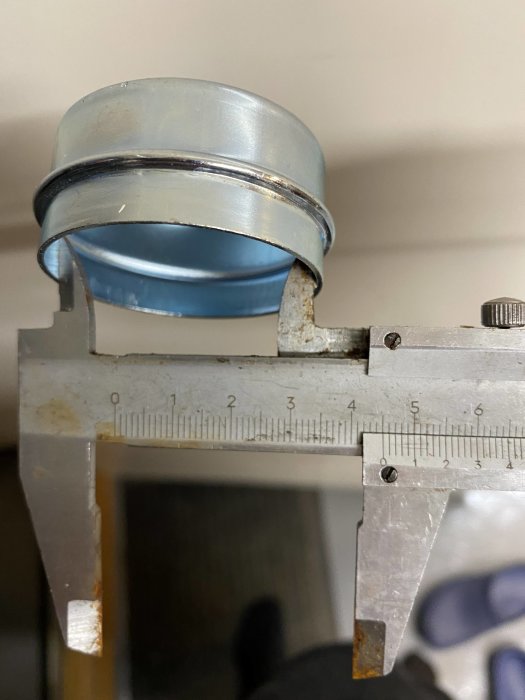 Skjutmått mäter diametern på en blå navkapsel, visar 45 mm på insidan.