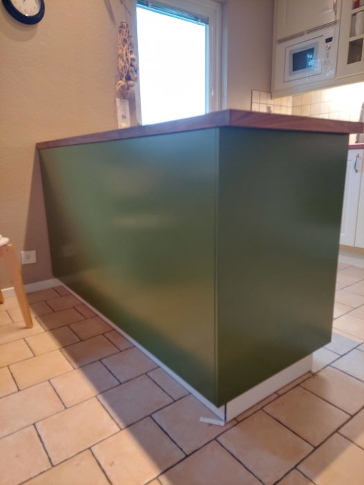 En grön halvö-möbel redo att användas som serveringsbord i ett kök.