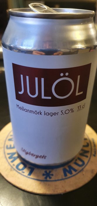 Aluminiumburk med etiketten "JULÖL Mellanmörk lager 5,0% 33 cl" på en brun underlägg.