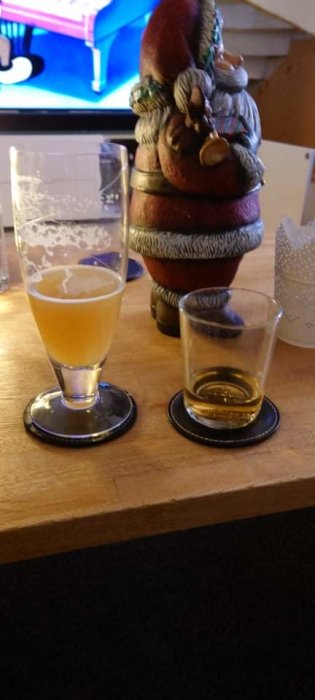 Halvtomt glas av Cloudwater öl och Plantation rom med julfigur i bakgrunden.