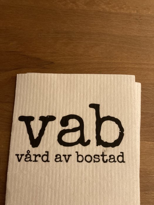 Servett med texten "vab vård av bostad" på ett träbord, skämtsamt för hemprojekt efter jul.