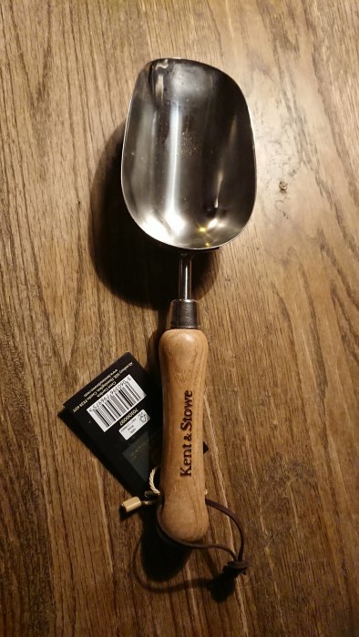 Ny trädgårdsspad med trähandtag på träbord, gåva för jordblandning.
