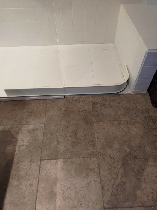 Renoverat badrum med dusch utan tröskel där vatten rinner ut, synlig dusch-sarg på golvet.