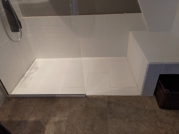Nybyggd duschhörna utan tröskel, med synlig glasvägg och dusch-sarg på golvet.