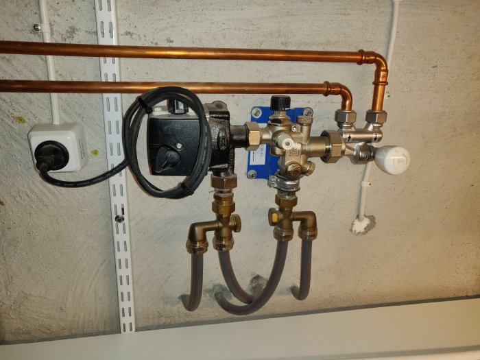 VVS-installation med en golvvärmeshunt, Danfoss-radiatorventiler och kopparledningar.