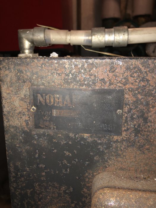 Rostig kombipanna med märkesplåt som visar texten 'NORA' och serienummer, indikerar trådens diskussion om pannreglering.