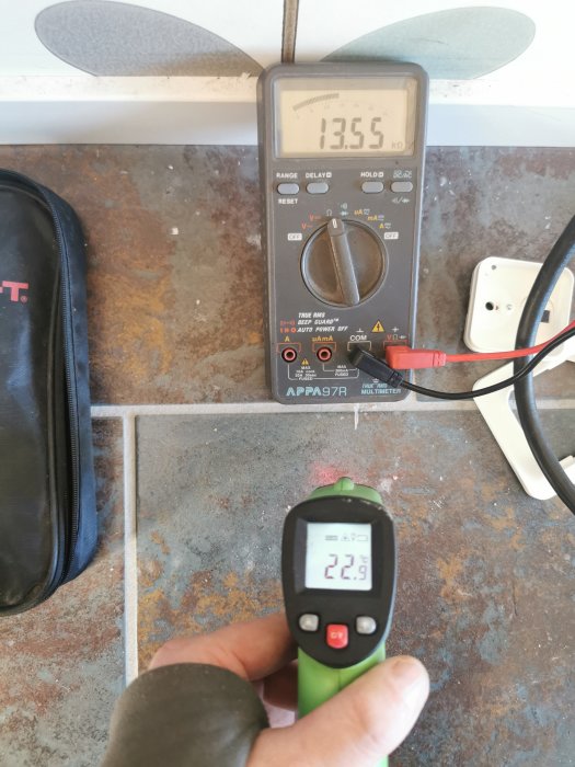 Multimeter visar 135,5 kOhm och infraröd termometer visar 22,9 °C vid golvtester.
