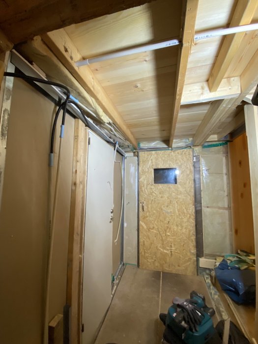 Renoveringsprojekt med synliga elkablar dragna längs takbjälkar i ett hus under ombyggnad.