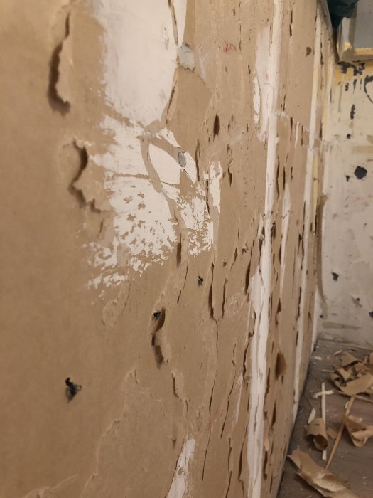 En vägg av lättbetong med rivna rester av vad som ser ut som gammalt tapet eller papper, redo för renovering.
