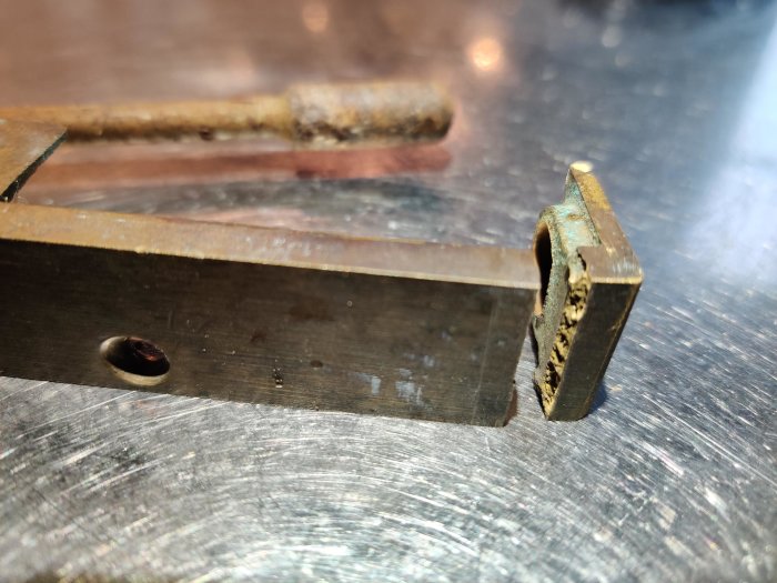 Närbild av en skadad mässingsdel från en ytterdörr som behöver reparation.